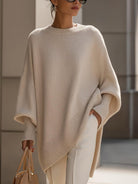 Celeste oversized poncho trui in beige met wijde vleermouwen en asymmetrische zoom