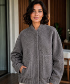 Vrouw in zwart oversized bouclé bomberjack — strakke afwerking