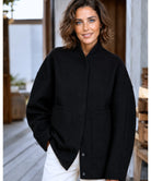Vrouw in grijs oversized bouclé bomberjack — zijdelings silhouet